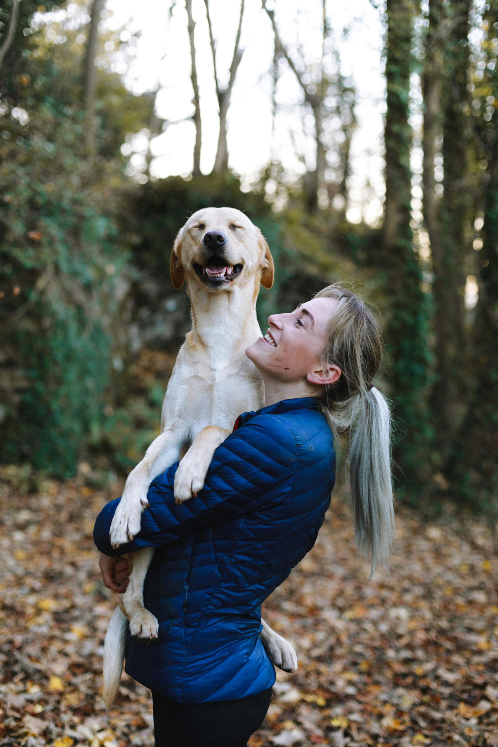 An active owner running with their dog along a woodland trail